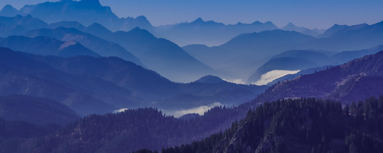 Paysage de montagnes et de vallées se déployant jusqu'à l'horizon, symbole de disponibilité, de perspective et d'exploration de nouveaux chemins.