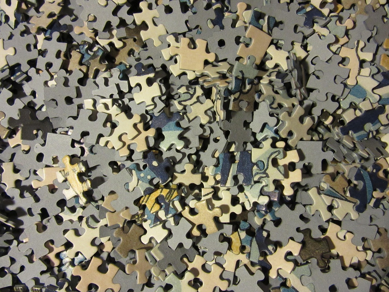 Pièces de puzzle dispersées illustrant des informations fragmentées en attente d'être reliées.