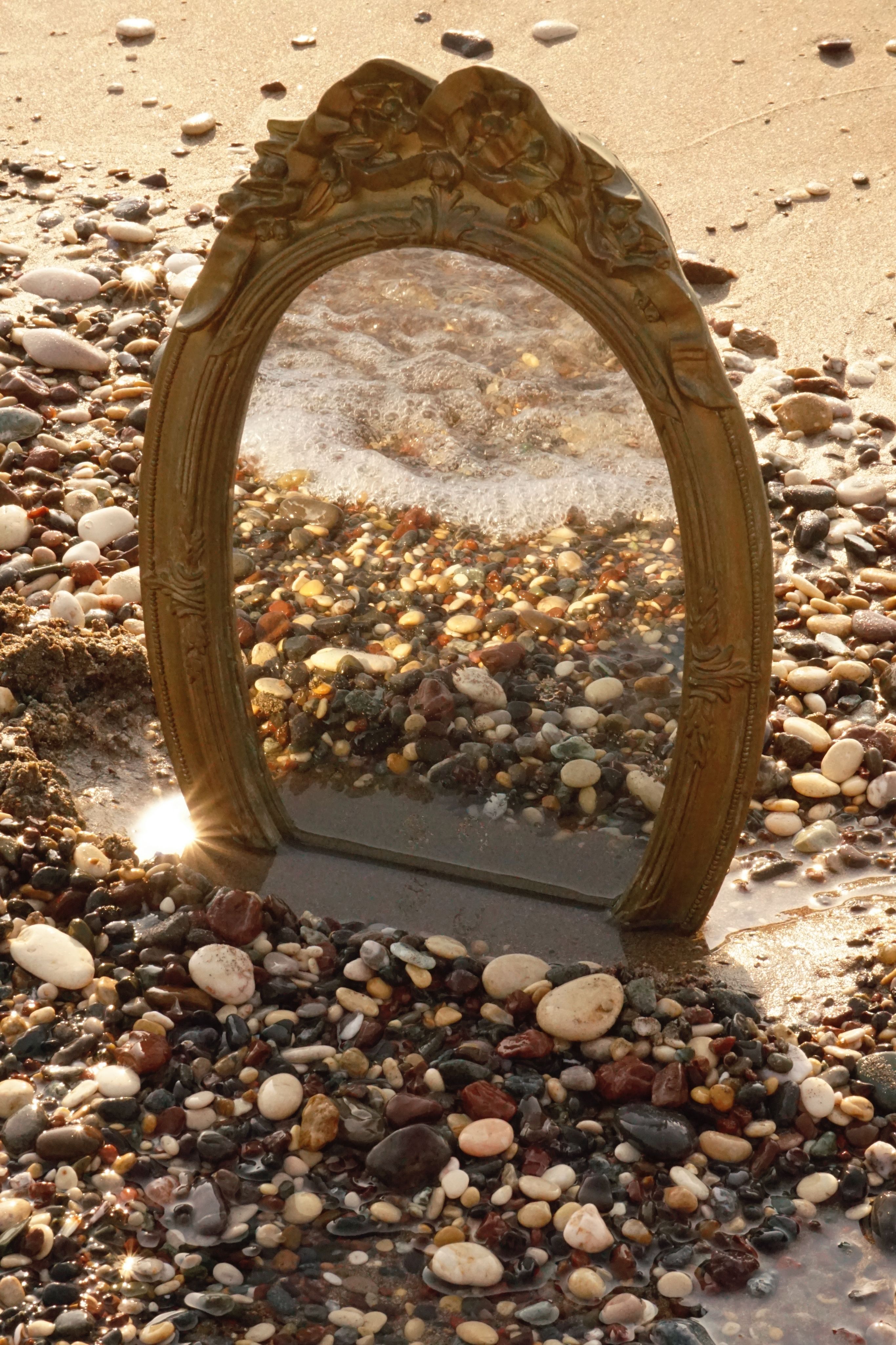 Miroir reflétant un paysage de galets et d'eau, symbole de la perception et de l'observation de soi